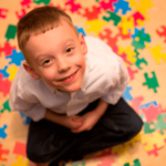 Imagem de criança senta da e sorrindo enquanto olha para cima - autismo