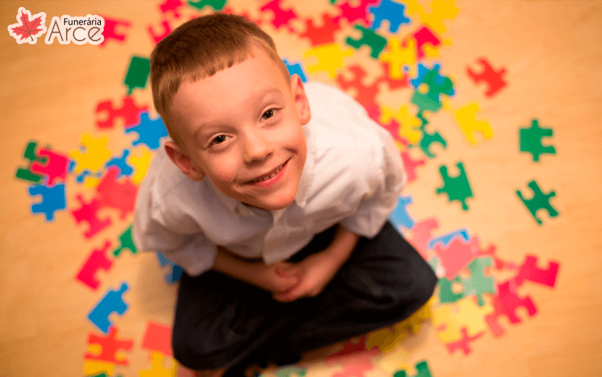 Imagem de criança senta da e sorrindo enquanto olha para cima - autismo