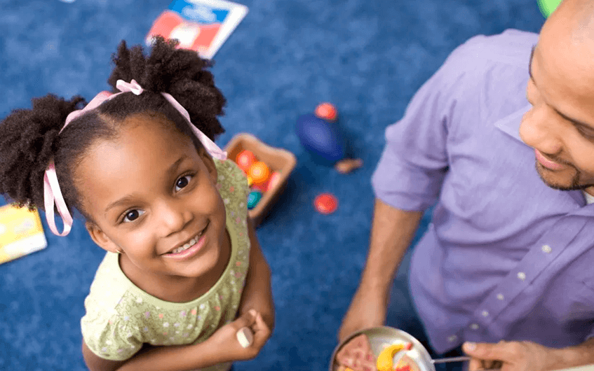 Menina sorrindo e olhando para cima ao lado do pai - autismo