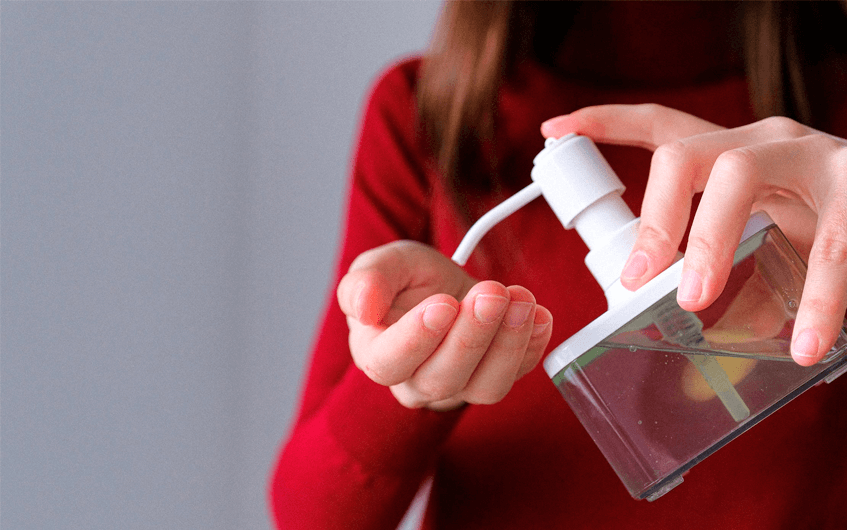 Mulher-aplicando álcool em gel na mão - coronavírus