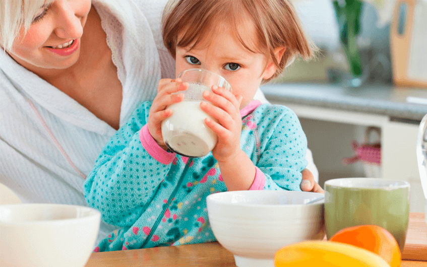 M"ae observando a filha beber leite - intolerância à lactose