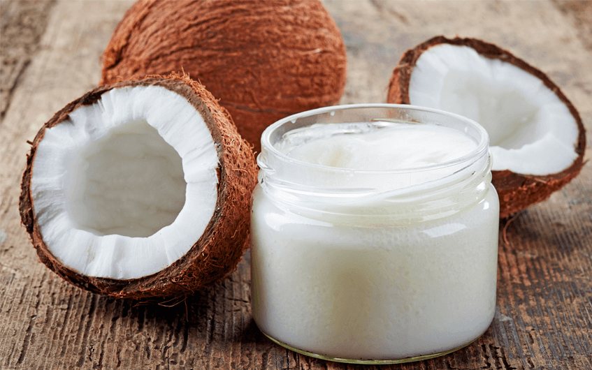 Coco in natura ao lado de pote com óleo de coco